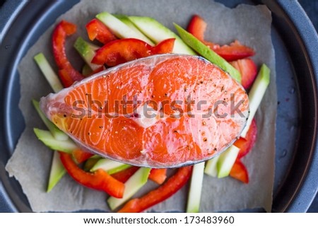 Cooking raw steak of red fish salmon on vegetables, zucchini, sweet pepper, tasty healthy dish