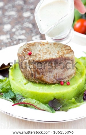 Grilled beef steak, green mashed potatoes with peas, herbs, pour out sauce
