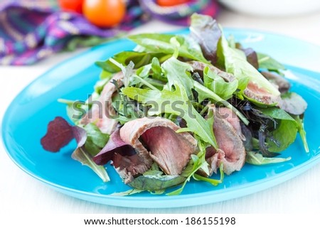 Green salad with grilled beef steak medium rare, mix lettuce, arugula, tasty fresh dish