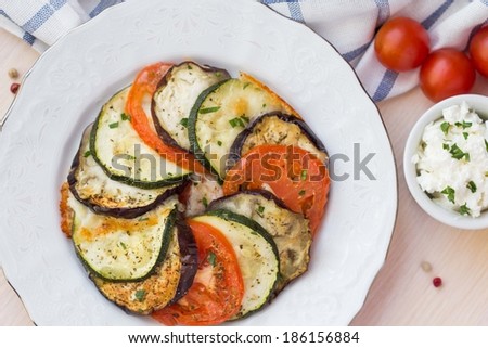 Ratatouille, vegetables cut into slices, eggplant, zucchini, tomatoes on plate, delicious vegetarian dish