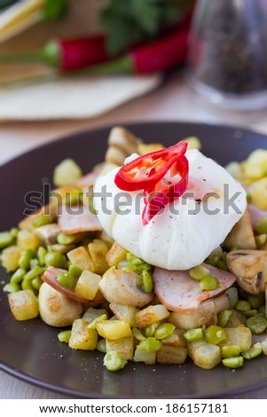 Hot appetizer salad with potatoes, ham, green peas, mushrooms, poached egg, tasty dish