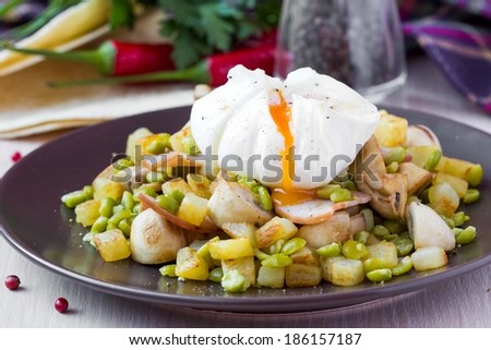 Hot appetizer salad with potatoes, ham, green peas, mushrooms, poached egg with resultant yolk