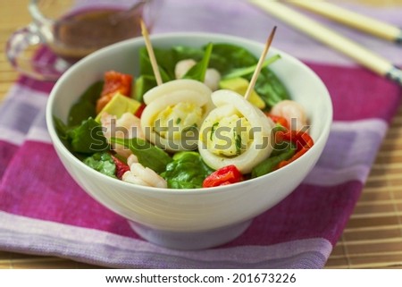 Asian salad with spinach, shrimps, pepper,avocado, rolls squid, rice, egg, tasty dish