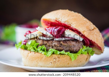 Burger, hamburger sandwich with cutlet of minced meat, cheese brie, camembert, berry cherry sauce