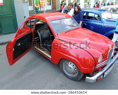 Voronezh, Russia - May 9, 2015: City dwellers look round sweden retro car of 1950s front-wheel drive Saab 93 with open door on the street near city square during the celebration of the Victory V-E Day