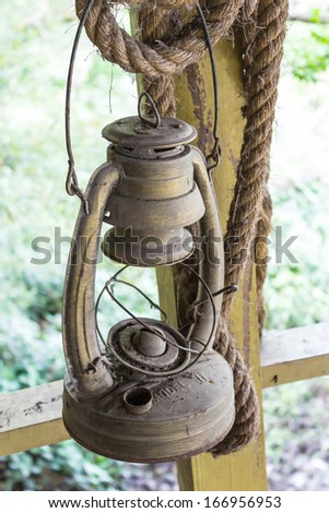 old rusty oil lamp hanging on a wood fence