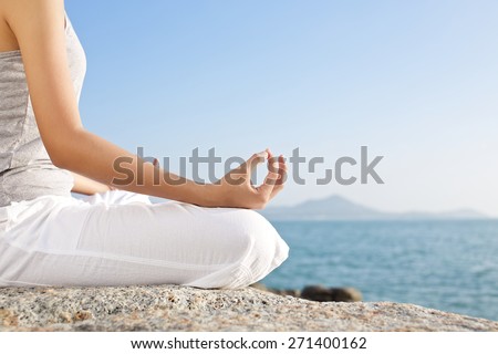 young woman meditation in a yoga pose on the tropical beach
