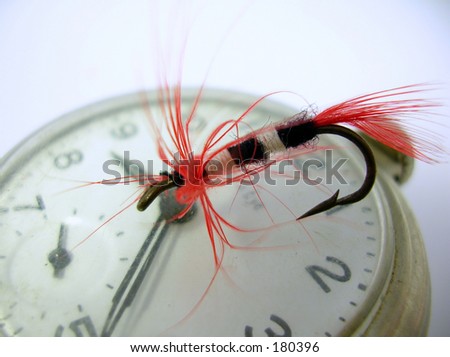 Macro of a hand-tied fly atop an antique pocket watch. \
\
\