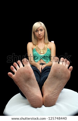 A lovely young blonde with dirty feet.  Selective focus on her feet.