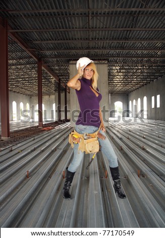 A beautiful blonde with a tool belt and hardhat in a partially completed commercial building.