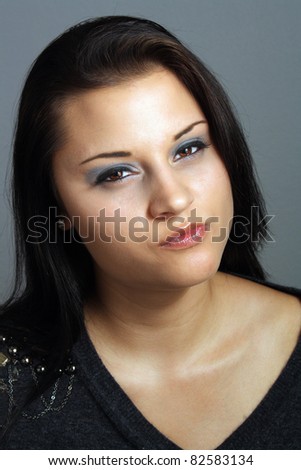 Close-up of a lovely brunette with a facial expression that could be serious, attentive, or irritated.