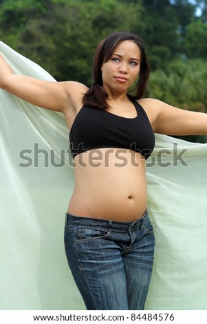 A lovely young multiracial woman, five months pregnant, enjoys the outdoor morning environment.