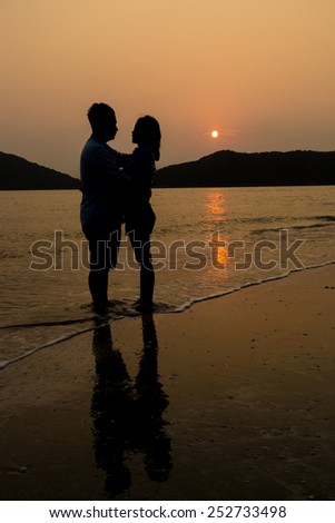 Couple hugging at the beach in sunset, silhouette