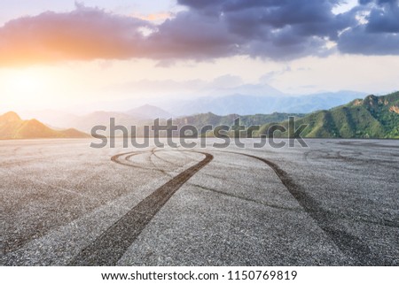 Empty asphalt square car tire brakes and mountain scenery at sunrise