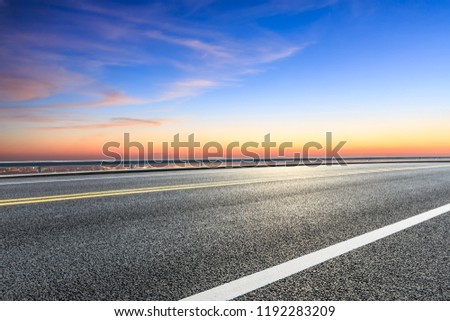 Modern city skyline and buildings with empty asphalt road at sunset