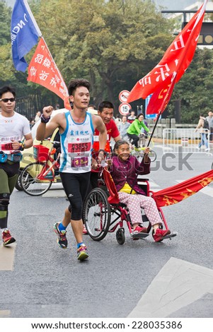 Hangzhou - November 2: international marathon,Chinese athletes Pull wheelchair old man in the running, November 2, 2014 in hangzhou, China. Hangzhou marathon is one of the most important game in China
