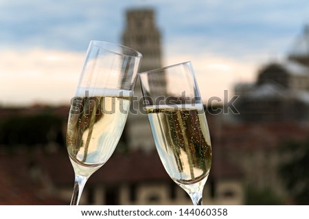 Two glasses of champagne with Pisa\'s Tower in the background