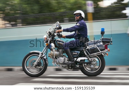 SANTIAGO DE CUBA, CUBA - APRIL 18, 2009. Police man riding motorbike while on duty patrolling the streets of Santiago de Cuba, Cuba on April 18, 2009.
