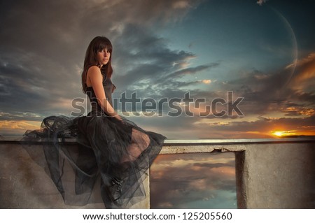 beautiful young woman sitting on the wall at moon