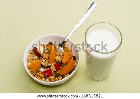 muesli with apples and peaches in a bowl on a napkin with a glass of milk