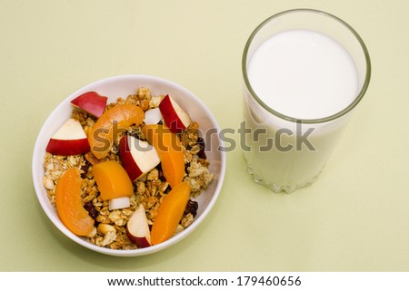 muesli with peach, apple and a glass of milk on a green napkin