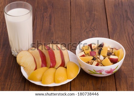 muesli with peach, apple and a glass of milk on wooden background