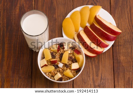muesli with peach, apple and a glass of milk on wooden background