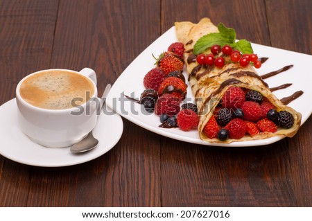 Crepes With Berries and cup of coffee . Crepe with Strawberry, Raspberry, Blueberry and Chocolate topping. Pancake