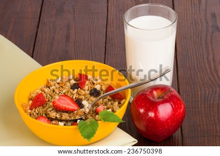 muesli with strawberries, apple and a glass of milk on a green napkin