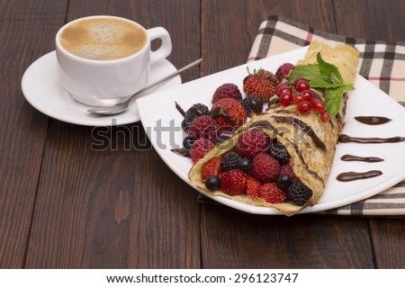 Crepes With Berries and cup of coffee. Crepe with Strawberry, Raspberry, Blueberry and Chocolate topping.Pancake