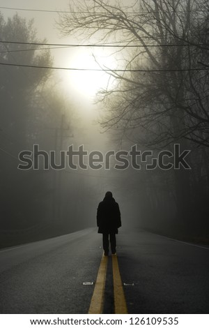 A Person Walk Into The Misty Foggy Forest Road In A Dramatic Sunrise Scene