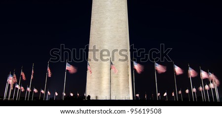 Washington Monument with waving United States flags at night