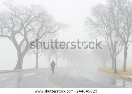 Road to fog and a man walks in to middle of road