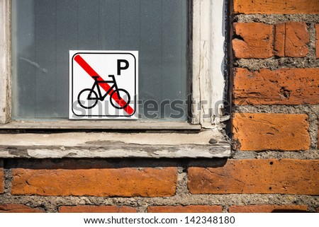 no bikes here: a \'no parking of bikes allowed\' sticker, on a window next to a brick wall