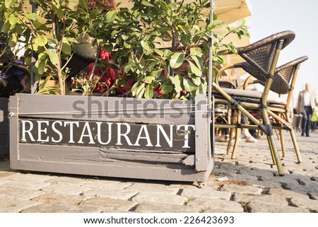 a flower box with a restaurant sign, next to outdoor seating