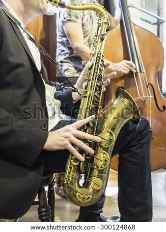 jazz duet (tenor saxophone and bass fiddles, unrecognizable musicians), performs live at jazz club (selective focus on saxophone)