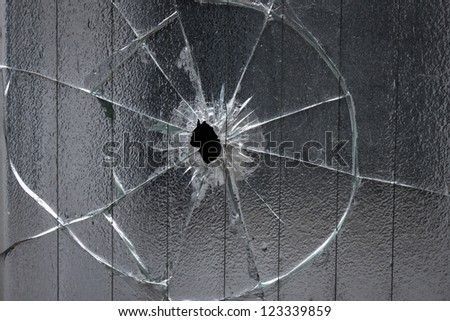broken window glass with a hole in the middle