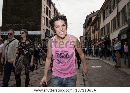 MILAN, ITALY - MAY 1: May Day parade in Milan MAY 1, 2013. A young woman gives a funny smile to the camera while people march in the streets for the traditional May Day parade