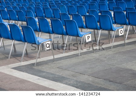 Blue plastic chairs in line with letters on a side