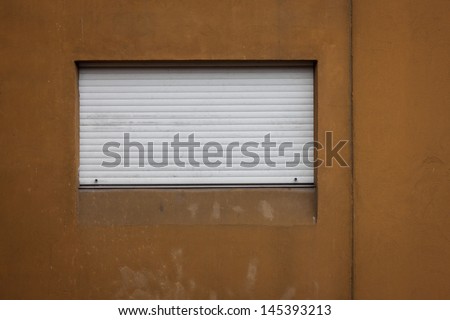 Window with rolling shutter on orange wall