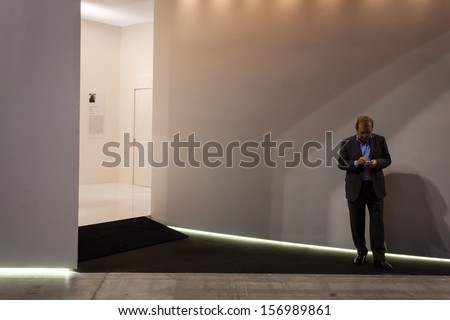 MILAN, ITALY - OCTOBER 3: A man alone with his phone at Made expo, international architecture and building trade show on OCTOBER 3, 2013 in Milan.