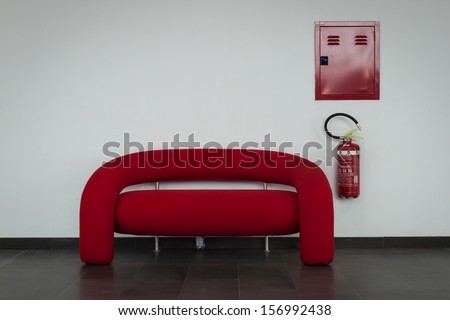 MILAN, ITALY - OCTOBER 3: A red couch with fire extinguisher at Made expo, international architecture and building trade show on OCTOBER 3, 2013 in Milan.