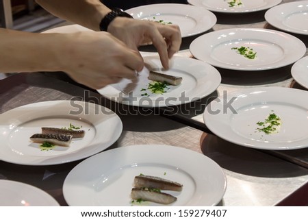 MILAN, ITALY - OCTOBER 18: Hands prepare food at Host 2013, international exhibition of the hospitality industry on OCTOBER 18, 2013 in Milan.
