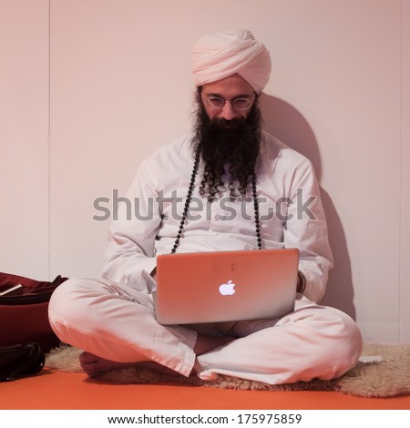 MILAN, ITALY - FEBRUARY 7: Bearded man with turban works on his notebook at Olis Festival, event dedicated to holistic disciplines, alternative medicine and natural food on FEBRUARY 7, 2014 in Milan.