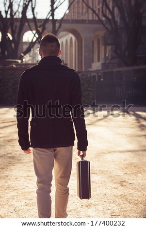 Handsome young man walking alone with a briefcase