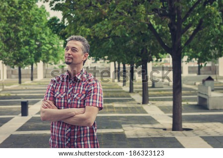 Man in short sleeve shirt standing in the street with crossed arms
