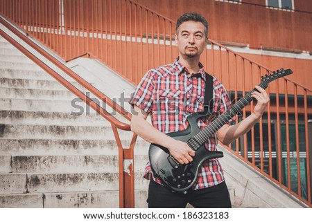 Man in short sleeve shirt playing electric guitar in the street