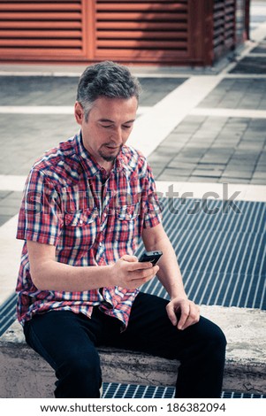 Man in short sleeve shirt texting on phone in the street