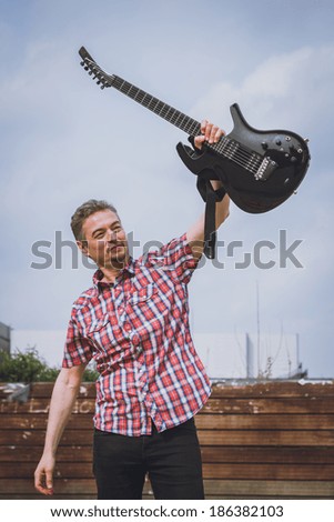 Man in short sleeve shirt holding electric guitar in the street