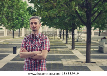 Man in short sleeve shirt standing in the street with crossed arms